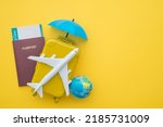Red umbrella cover airplane, passport, flight tickets and suitcases travelers on yellow background. Travel insurance covers loss suitcase, flight delays, cancellations, accident and medical expenses.