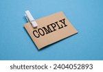 Small photo of Comply text written on a notebook with blue background.