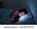 Small photo of In the throes of sleeplessness and digital allure: A young lady, ensnared in her bed, turns to her smartphone for solace