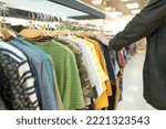 Small photo of Man shopping at clothes marketshop. Mew fashion collection at fashionable clothes store. Clothing rental or thrift shopping concept. Secondhand store with clothes on hangers