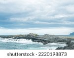 rocky seashore formed by columnar basalt against the backdrop of a stormy sea, coastal landscape of the Kuril Islands