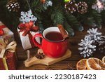 Christmas mood, holiday atmosphere. Red cup of coffee, fir branches with cones, Christmas gifts, star anise on a wooden table background.