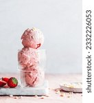 Small photo of Yummy stake of strawberry ice cream scoops in a glass bowl on a table