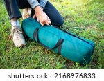 A woman opens a cover with a tent on the grass. Close-up of her hands unzip the zipper. Tourism concept. Trekking and camping.