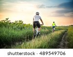 Man and woman riding bicycles in a field at sunset in the fall, summer. The girl and the guy on the bike involved in cycling. Walk on bicycles outdoors.