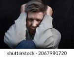 Small photo of Portrait of a man going through a grievous moment in his life. The concept of drama, experience, pain. On a dark background. Selective focus