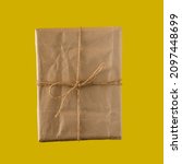Small photo of gift made of kraft paper tied with thine on a dark yellow background. flat lay.