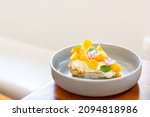 Small photo of Crumble Mango Cheese Pie in Japanese ceramic dish decorated with mint leaves and eggplant flowers, placed at the corner of wood table, warm light, white background, front view, horizontal, copy space