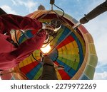 Low angle view - man operating hot air balloon, giving it a boost in flight