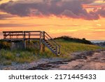 Lovely Cape Cod beach scene with colorful sunlit clouds and sun about to drop below the horizon. Vibrant summer sunset captured at Corporation Beach in Dennis, Massachusetts.