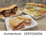Small photo of Handmade from fresh ingredients deli sandwiches with the featured reuben corned beef on rye bread in front of tri tip and classic Italian sub.