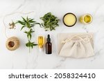 Small photo of Cannabis products. Cannabis medical healing balm salve, CBD and food oil bottles, tea leaves, sativa seeds, hemp rope and fabric bag. Top view composition with hemp plant on marble background