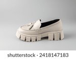 Small photo of Trendy fashionable beige leather women platform boot, loafers on neutral grey background. Casual spring or summer comfort style.