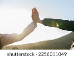 Happy caucasian young woman giving high five to female friend while hiking together in woodland during sunrise