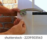 screwing bolts in the structure of the door handle on a light canvas by hand close-up, tightening the fasteners when installing the door mechanism with a hex key