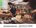 Small photo of Close up of a hand holding a filter holder with ground coffee that already tamp an espresso machine or coffee machine in coffee shop. A professional barista. Concept of Preparing process of coffee.