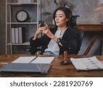 Asian business woman is using smartphone for searching or watching social media to entertain while breaking time at workplace. Female manager is chat with her friend during break time. Online shopping