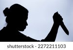 Small photo of Shadow of a woman with knife in hand with suspicious activity or going to stab someone to death.