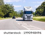 Small photo of A large HGV vehicle traveling along one of the main road routes of the United Kingdom, on a summer's day. Taking goods to and from their suppliers and customers.
