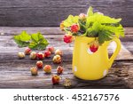 Small photo of Sprigs northern cloudberry keep pace with red berries in a ceramic mug on a simple wooden background. Useful rare berries growing in the north