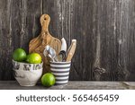 Simple kitchen still life on a background of a wooden wall on a shelf with cutlery, tools, marble bowls and juicy limes. The concept of home comfort food and comfort.