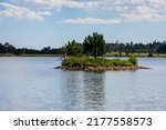 Small photo of Island in the middle of Dowdy Lake in Colorado. Blue sky, white clouds, island with trees and rocky shore. Reflection on calm water.