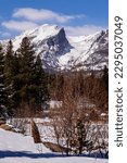 Small photo of Snow drifts pile in Colorado winter scene. Bushes in the foreground of Hallett Peak. Rocky Mountains of Colorado. Snow drifting on Sprague Lake with pine trees and bushes in the foreground.