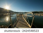 Small photo of SIlverthorne, Colorado, USA - August 12, 2022. Boats moored on Lake Dillon I Colorado. Blue sky, blue water and tall masted boats with reflection in clear water. Sun star with solar flare.