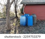 Small photo of Catching plastic rain barrels in front of a garden shed for water.