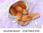 Home baked burger buns, small breads with shiny crust in white breadbasket and on wooden board. Delicious sandwich breads. Fresh baked bread rolls with soft crust and fluffy crumb. 