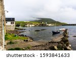 Small photo of Nolsoy island harbor with boats and small houses, Nollywood sign on a hill. Faroe Islands, Denmark.