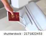 A hand holding Russian passport and suitcase 