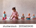 Beautiful smiling little baby sitting on potty. Cute adorable funny child girl using chamber pot together with her baby doll. Toilet training concept. Toddler learning to use the Toilet.
