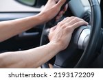 closeup of hand of driver pressing car horn button in car