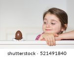Small photo of Little girl with an impish smile looking at the chocolate egg