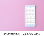 White smart phone show calendar App 2023 on pink background. New Year Concept.