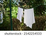 Towel and white sheet hanging on a rope outside to dry in the open air. Clothesline.