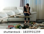 Small photo of Sad tenant complaining after home robbery sitting on a couch in the night with messy living room