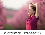 Relaxed runner stretching arms after exercise in a pink flowered field