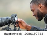 Side view portrait of a satisfied man with black skin checking photos on mirrorless camera