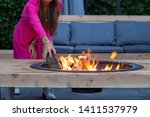 Woman Throws Logs On Fire Pit...