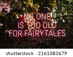 No one is too old for fairytales - neon sign on a wall at an outdoor wedding party. Love concept