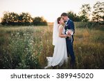 couple in wedding attire with a bouquet of flowers and greenery is in the hands against the backdrop of the field at sunset, the bride and groom