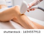 close-up woman's perfect legs while getting hair removal procedure in salon. professional beautician or cosmetologist use special ointment and apparatus. soft and smooth hairless skin on legs