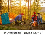 Small photo of positive group of people on hiking, caucasian women and man talk, drink tea andhave a good tome in the autumn forest