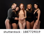 five smiling laughing beautiful women in bodysuit standing together, having fun, look at camera, isolated on black studio background