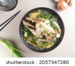 Small photo of Ayam Kuah Jahe or Samgyetang or Ginseng Chicken Soup, traditional Korean chicken soup with ginseng, ginger, garlic and leek served on black bowl.