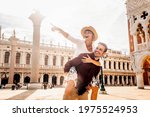 Couple of tourists on vacation in Venice, Italy - Two lovers having fun on city street at sunset - Tourism and love concept