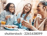 Small photo of Three young women enjoying breakfast drinking coffee sitting at bar cafeteria - Life style concept with female friends hanging out on city street - Food, beverage and friendship concept