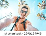 Happy tourist taking self portrait outside with cellphone on summer vacation - Handsome young man laughing at camera enjoying summertime day out - Tourism, traveler life style and technology concept